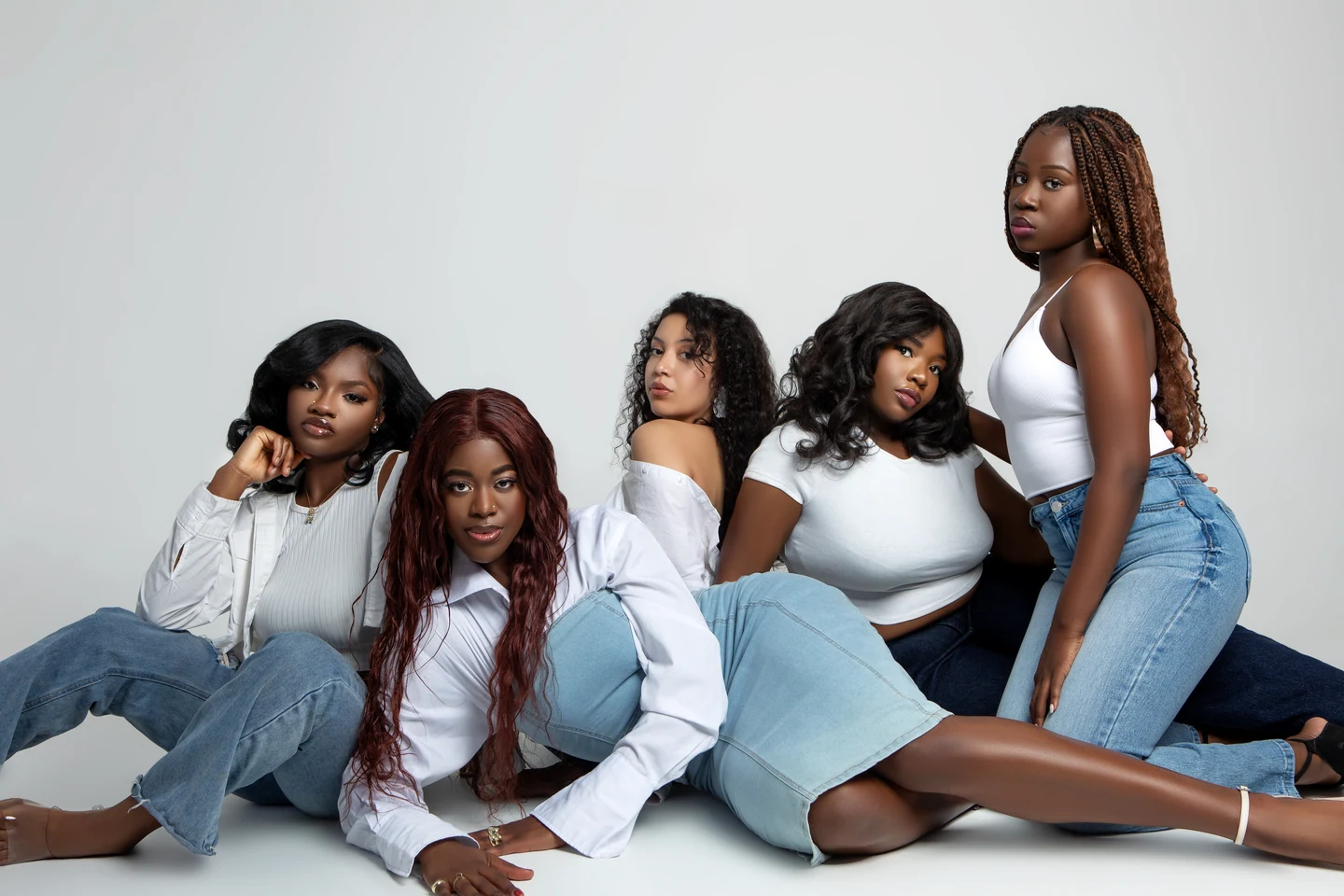 Cinq femmes en denim et hauts blancs dans une composition de groupe en studio.