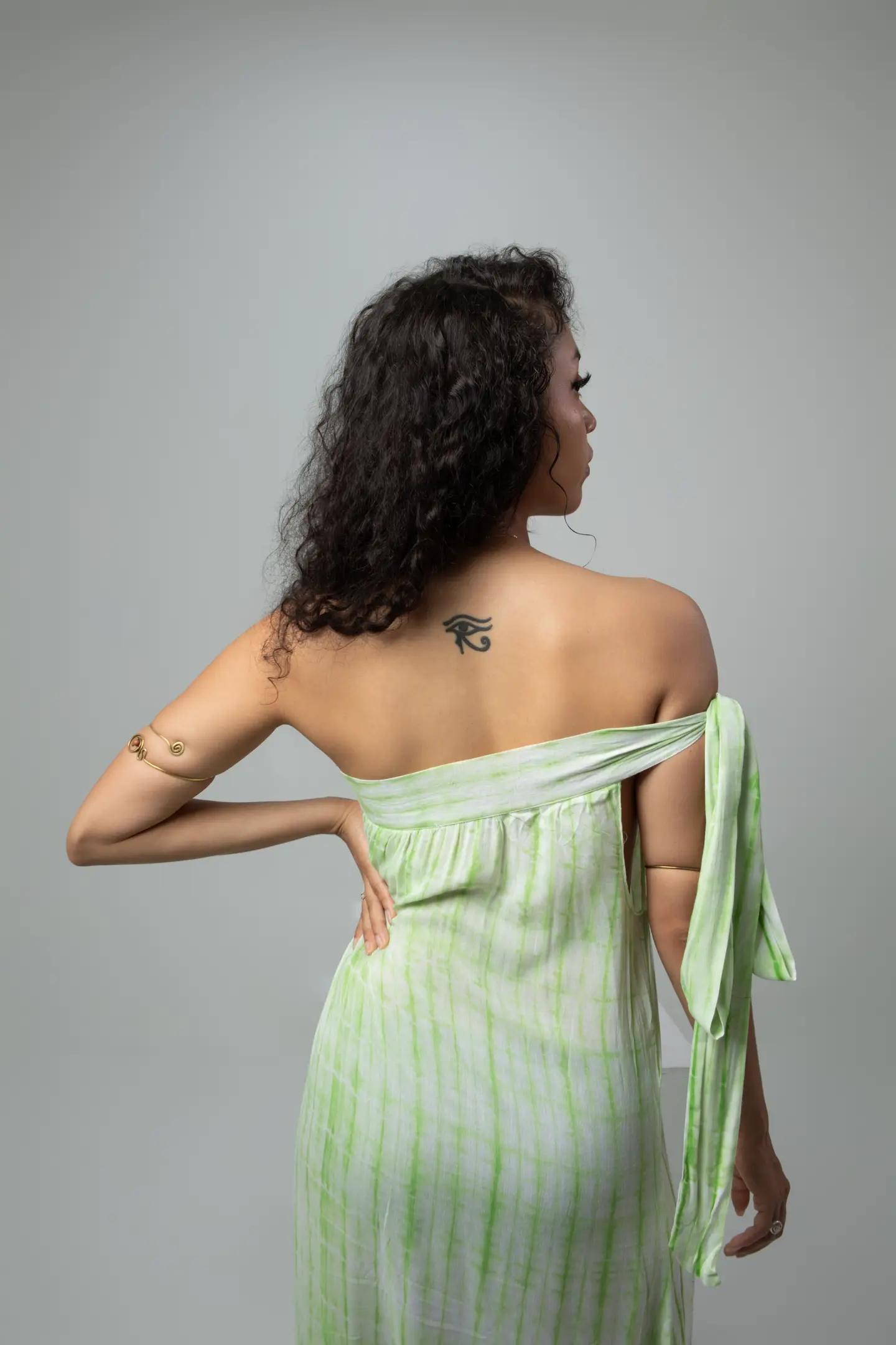 Vue de dos d’une femme en robe vert menthe, révélant un grand nœud dans le dos.