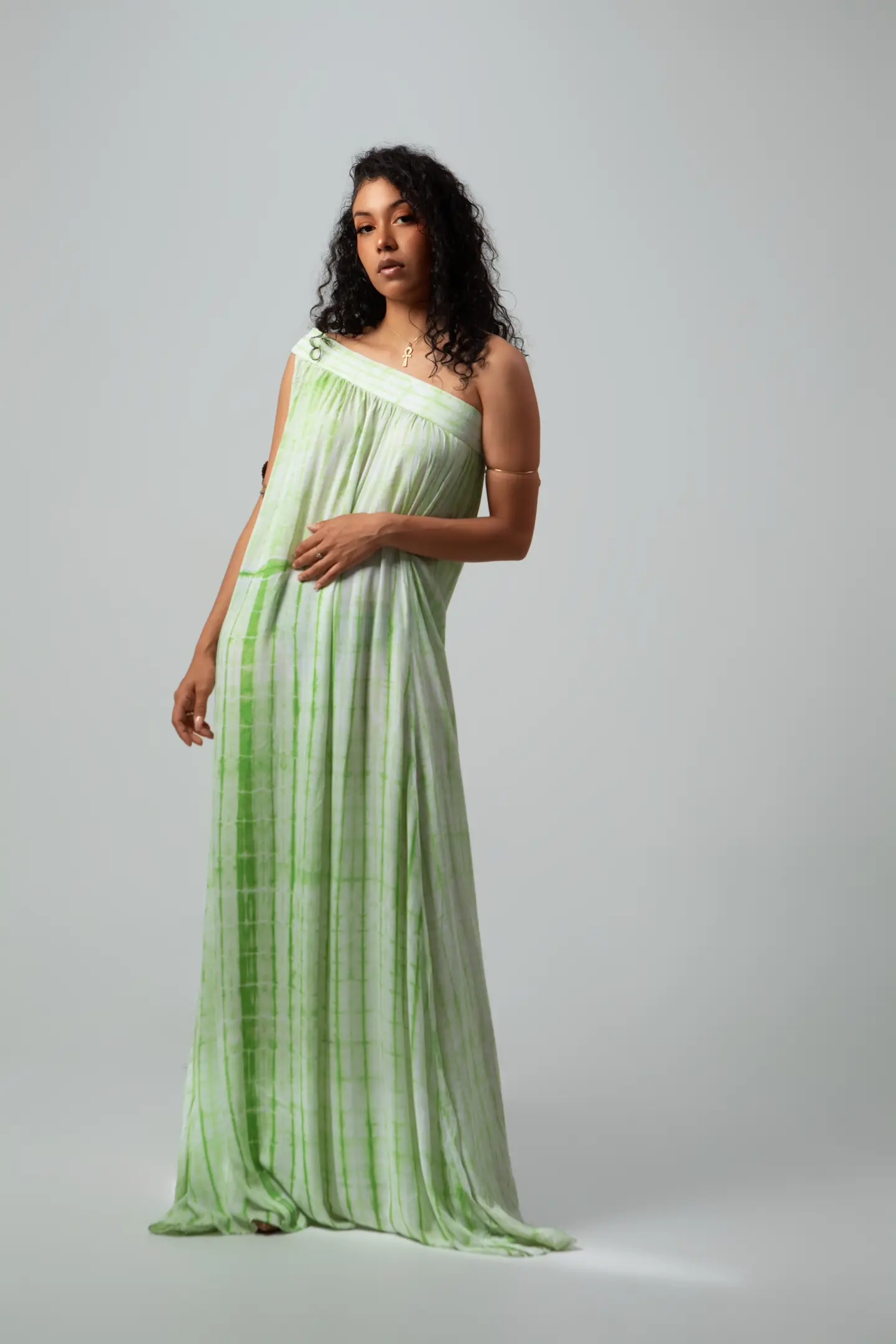 Femme en longue robe vert menthe photographiée en pied sur un fond gris de studio.