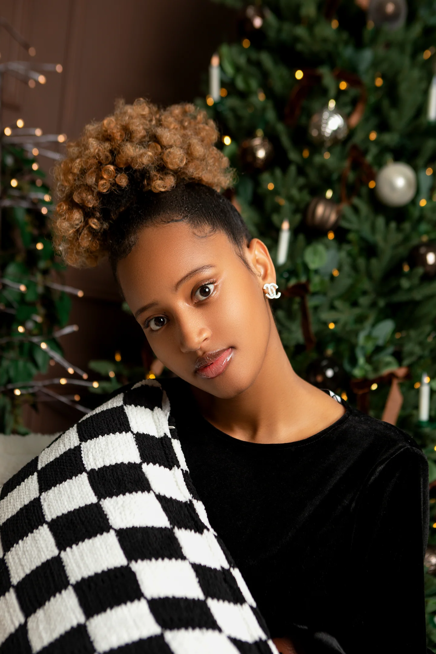 Un portrait de fête devant un sapin décoré, avec une écharpe à damier noir et blanc.