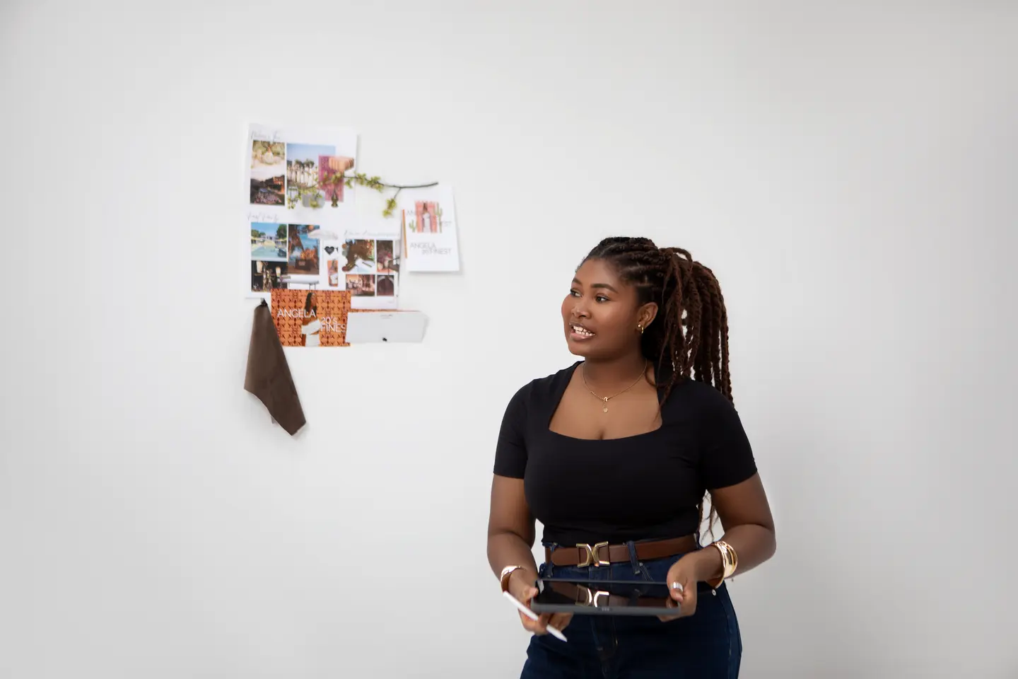 Femme assise avec une tablette devant un tableau d’inspiration dans un studio lumineux.