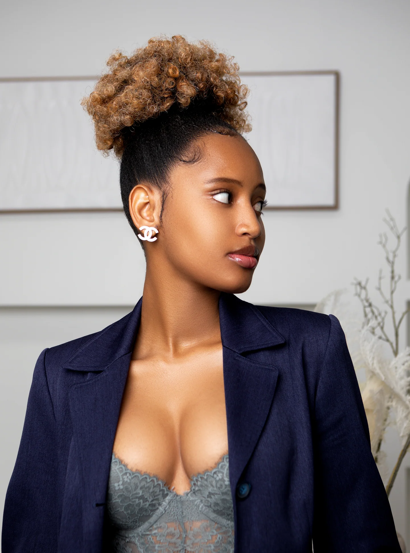 Portrait rapproché d’une femme en veste bleu marine, les cheveux relevés, regardant de côté.